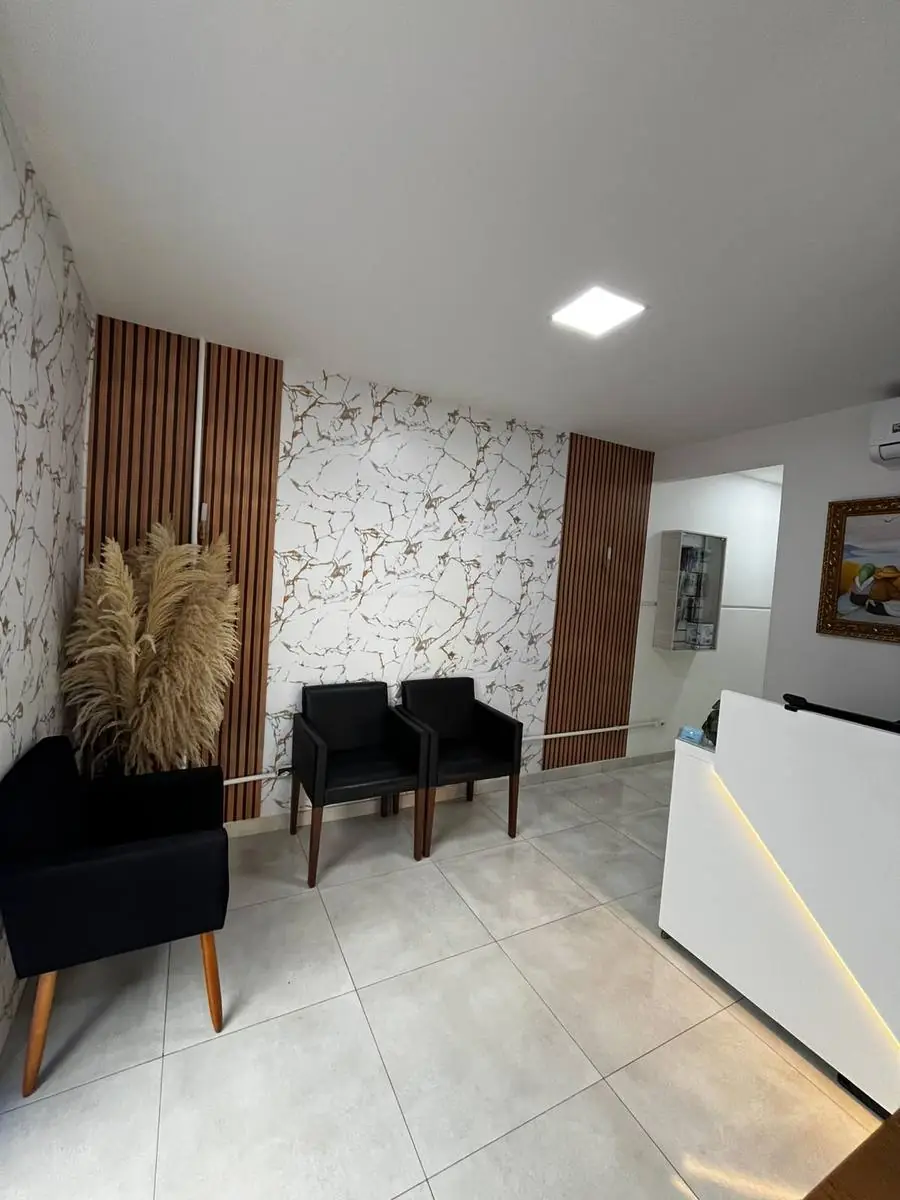 Sala de espera com poltronas pretas e decoração em mármore e madeira